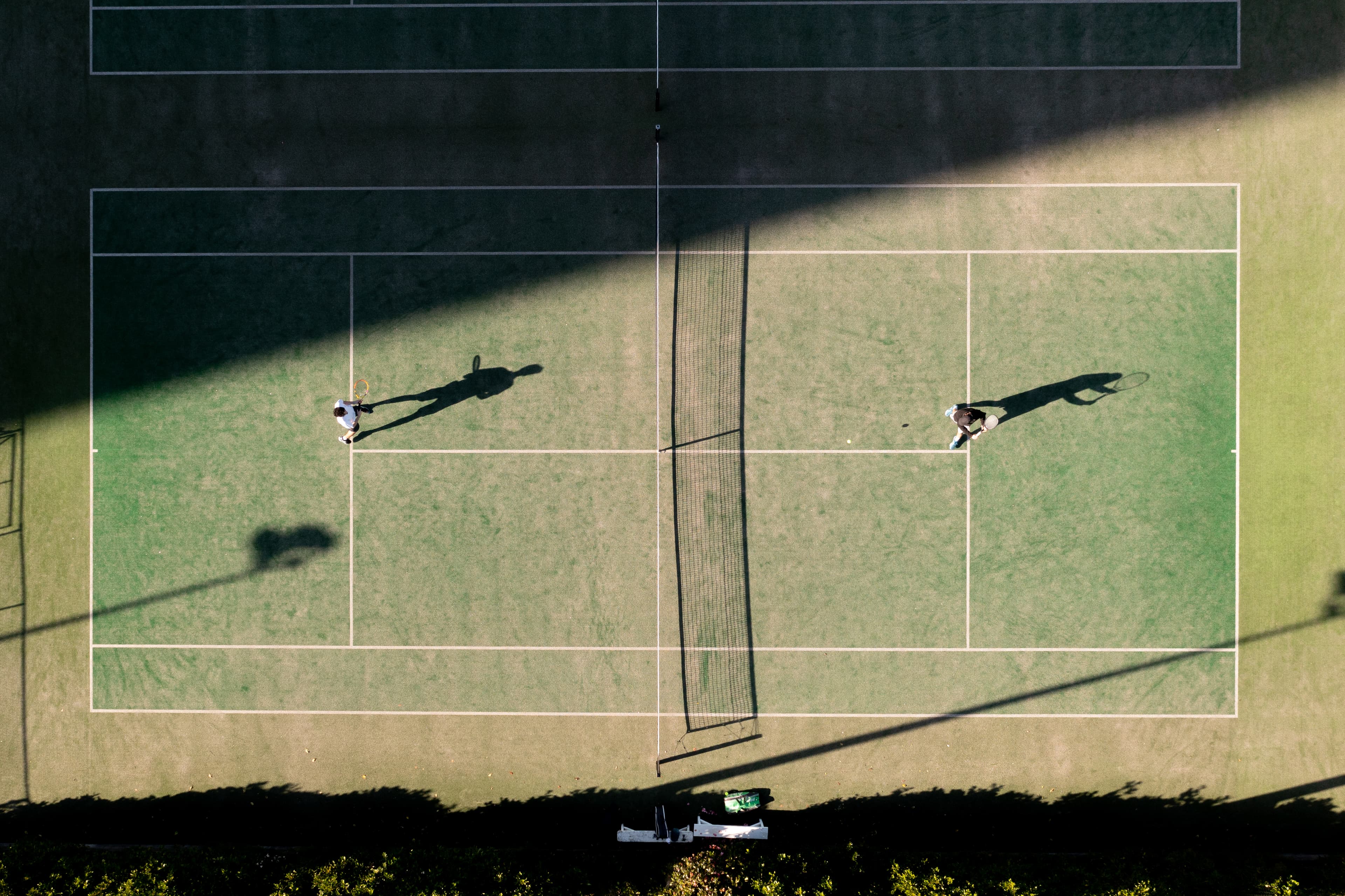 Two tennis players practising on a court viewed from above